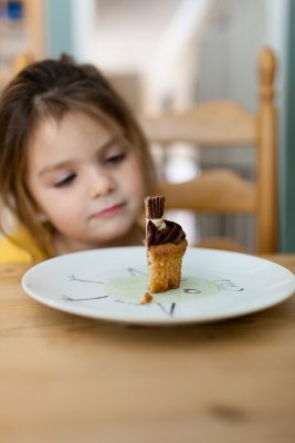 Receita de Muffin: menina olhando um Muffin servido em um prato.